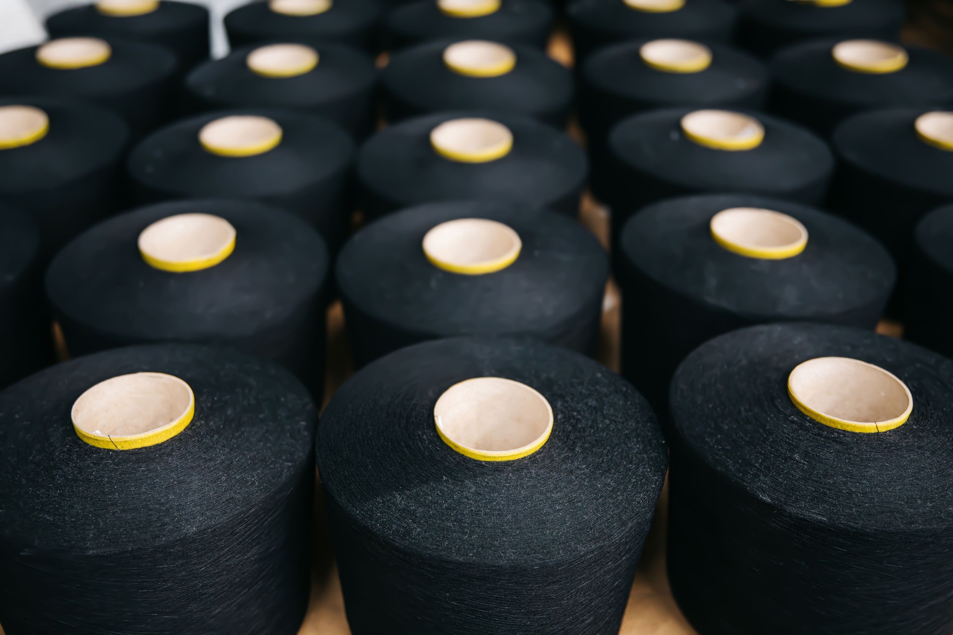 Black cotton yarns or threads on spool tube bobbins at cotton yarn factory.