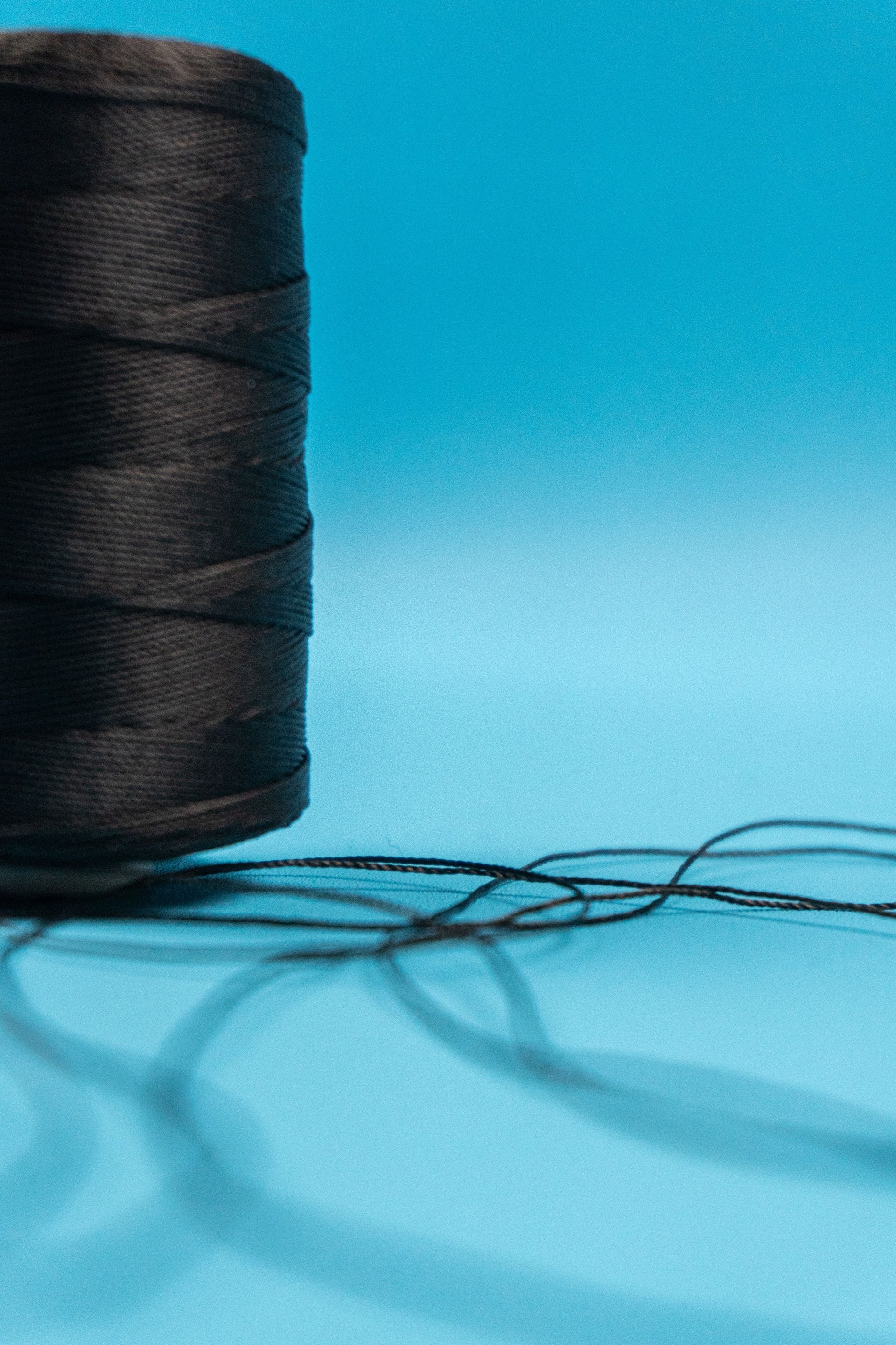 A spool of black sewing thread in a tailor shop on blue background